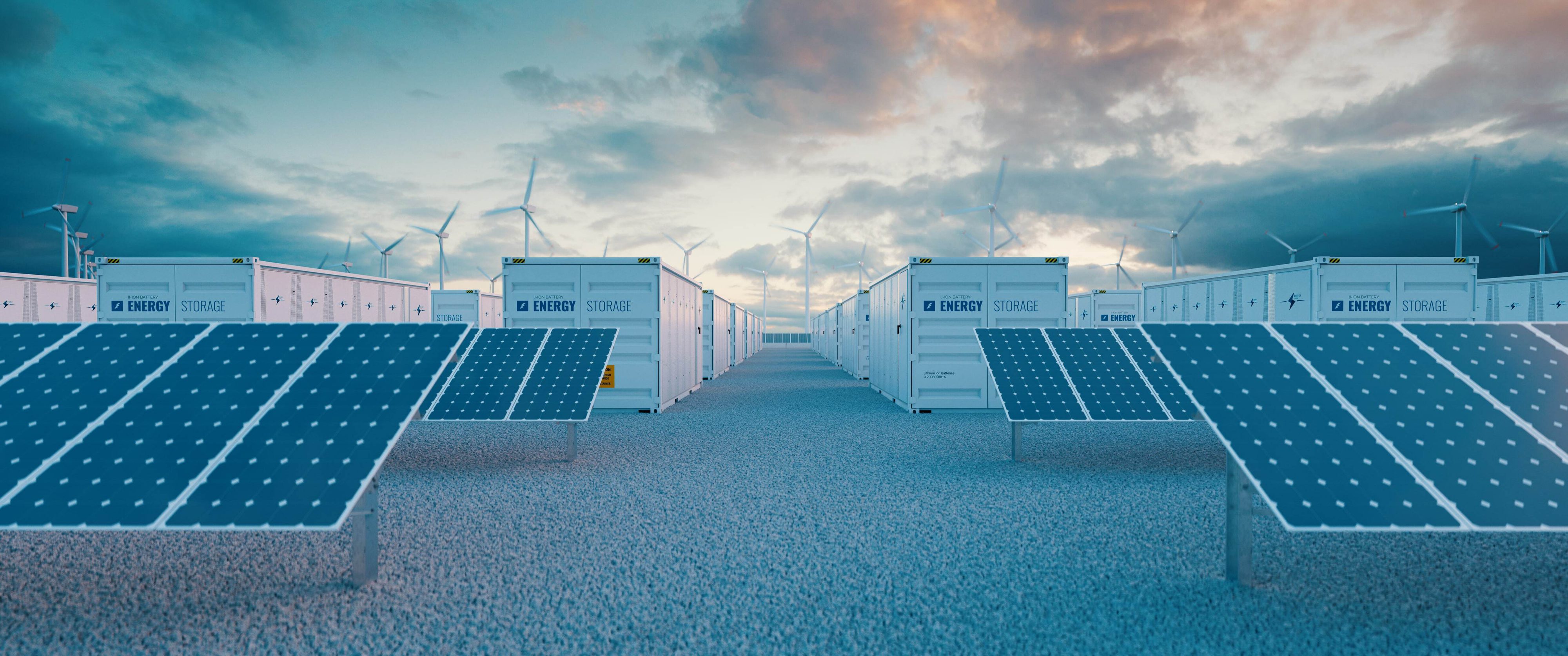 A renewable energy facility with rows of solar panels in the foreground and energy storage containers lined up in the background, under a cloudy sky with wind turbines visible in the distance.