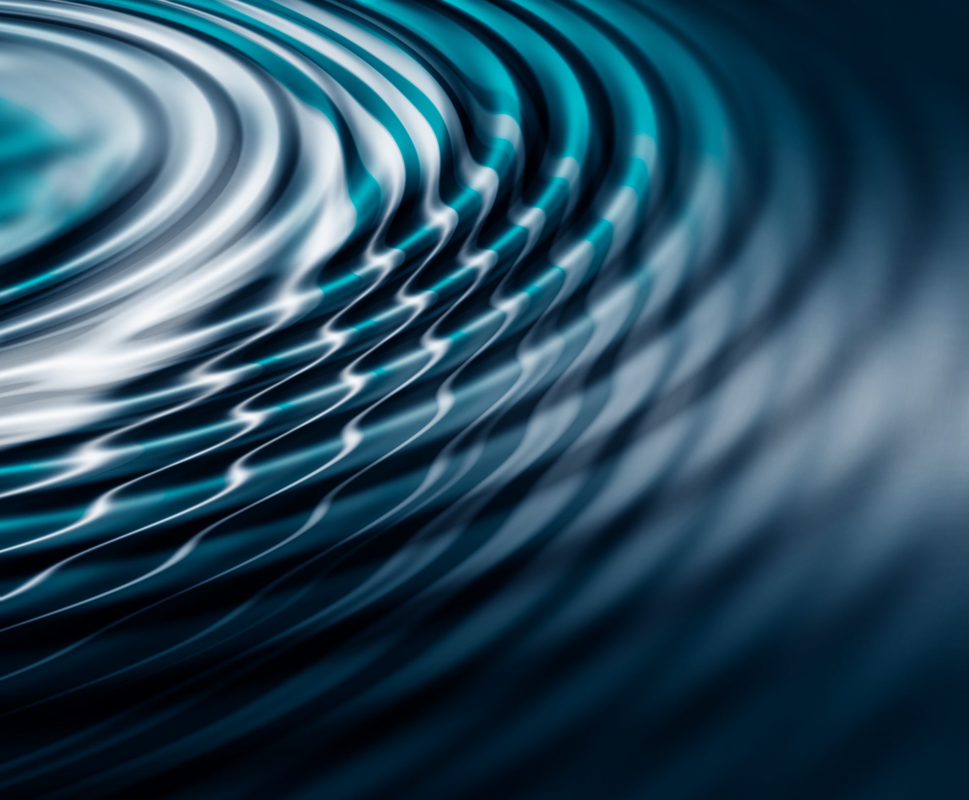 Close-up of rippling water creating concentric circular patterns with varying shades of blue and white, focused on the texture and movement of the surface.