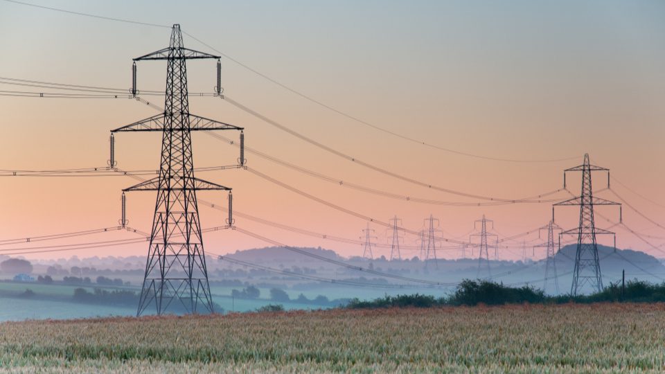 Electricity pylons and lines above farmland , England