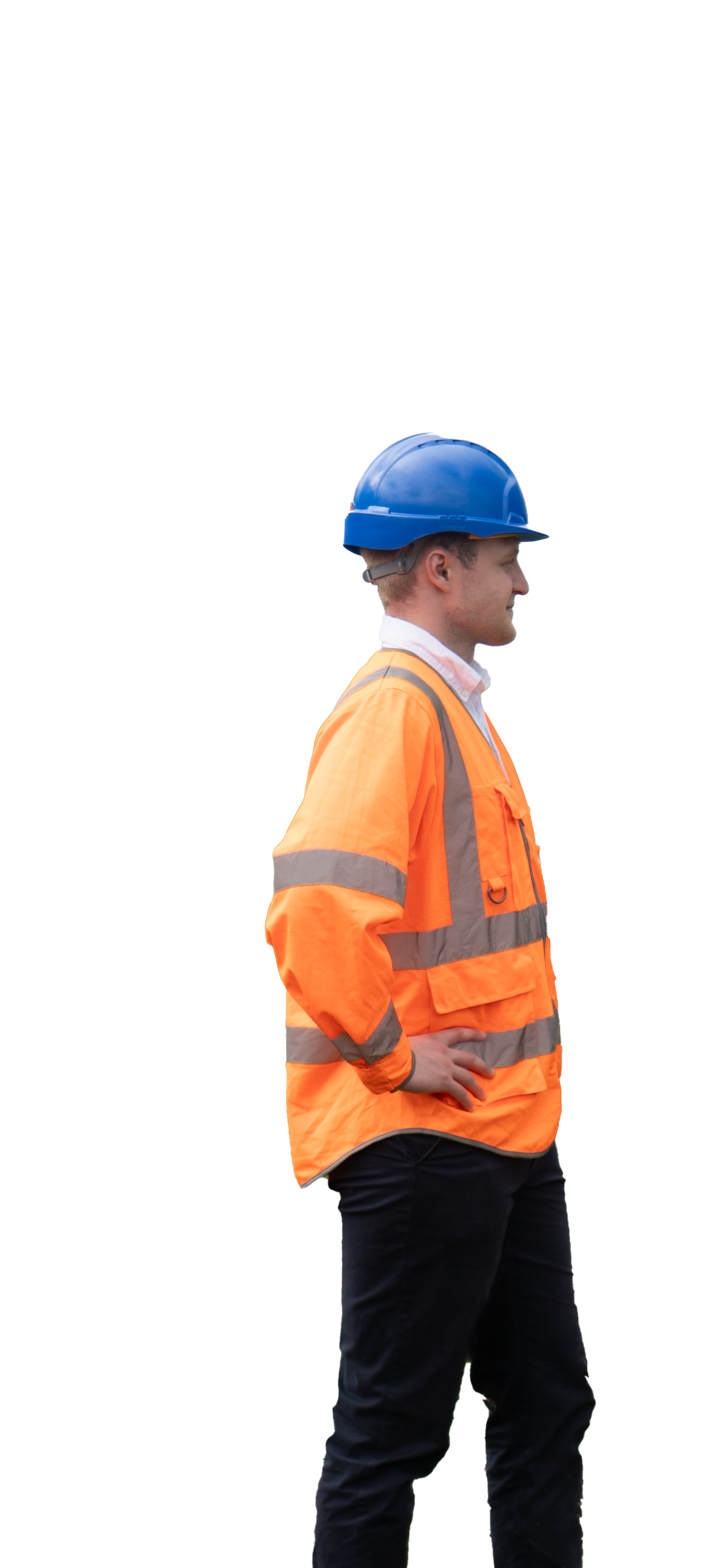 A man wearing an orange safety jacket with reflective stripes and a blue hard hat, standing sideways with hands on hips against a plain background.