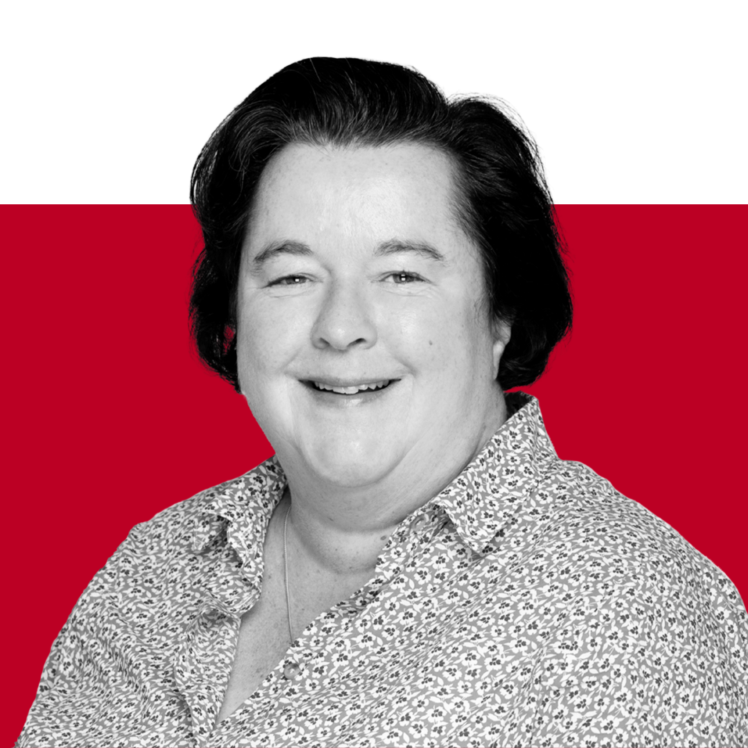 A smiling woman with dark hair, wearing a patterned shirt, against a red and black background.
