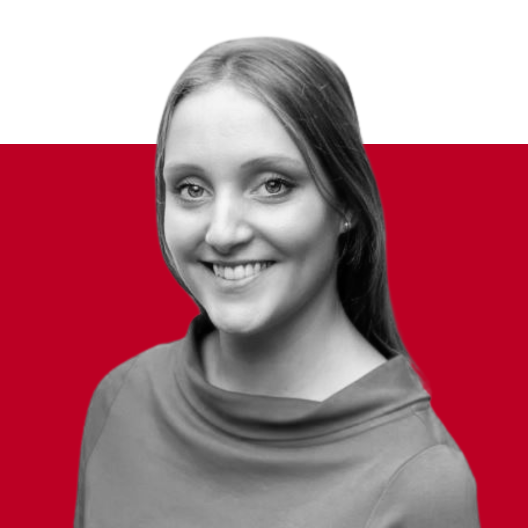 A smiling woman with long, straight hair wearing a collared shirt, positioned in front of a black and red background. The image is presented in black and white, emphasizing her facial features.