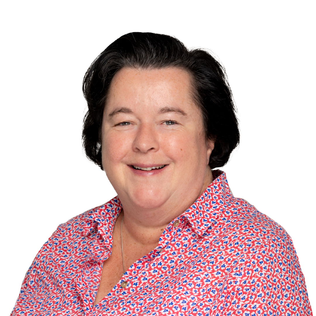 A woman with curly black hair is smiling while wearing a floral-patterned shirt. The background is solid white, highlighting her cheerful expression.